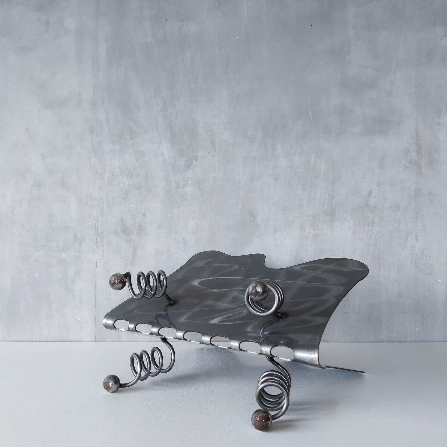 Vintage 1990s postmodern welded steel sculptural magazine rack with spiral ball feet