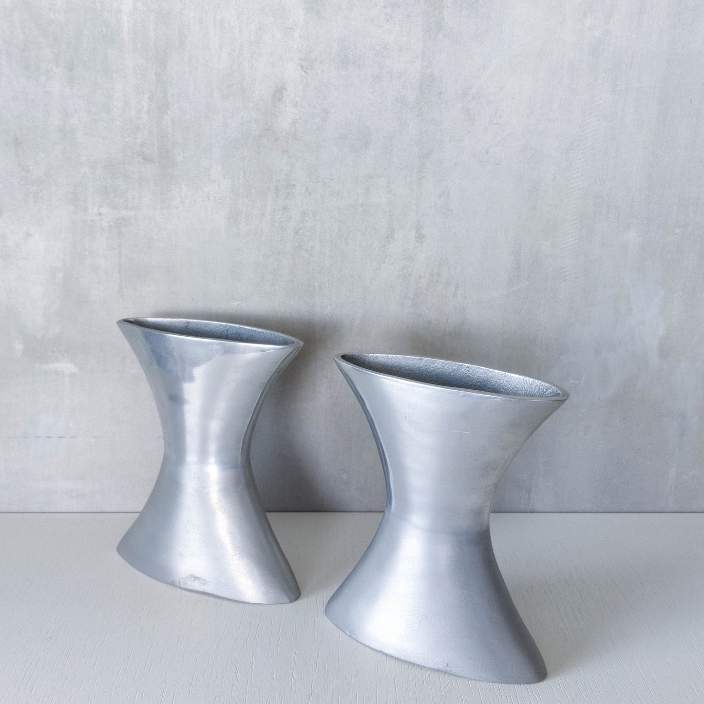 A pair of vintage sculptural cast aluminium flattened vases