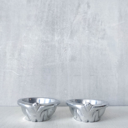 A pair of Carrol Boyes small figural cast aluminium bowls or tea light holders