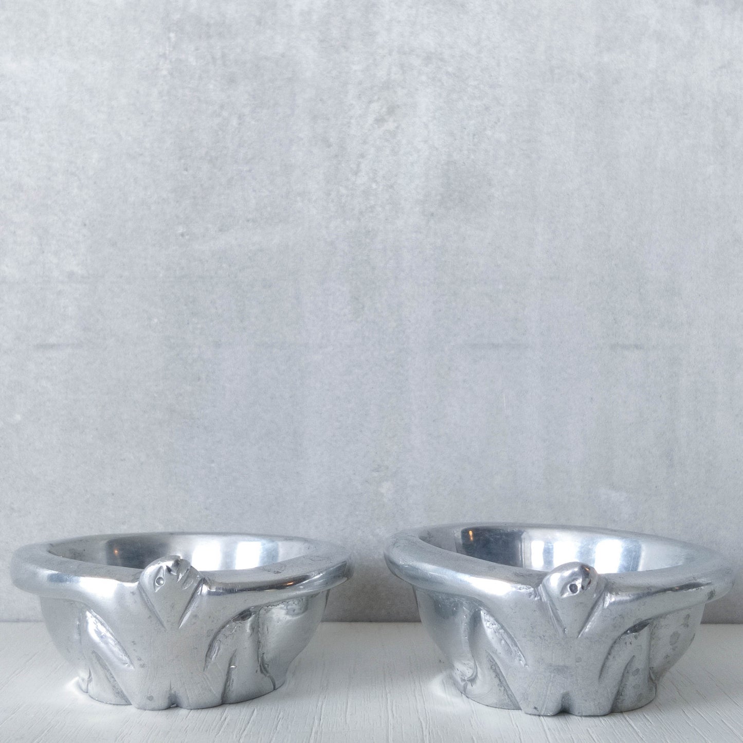 A pair of Carrol Boyes small figural cast aluminium bowls or tea light holders