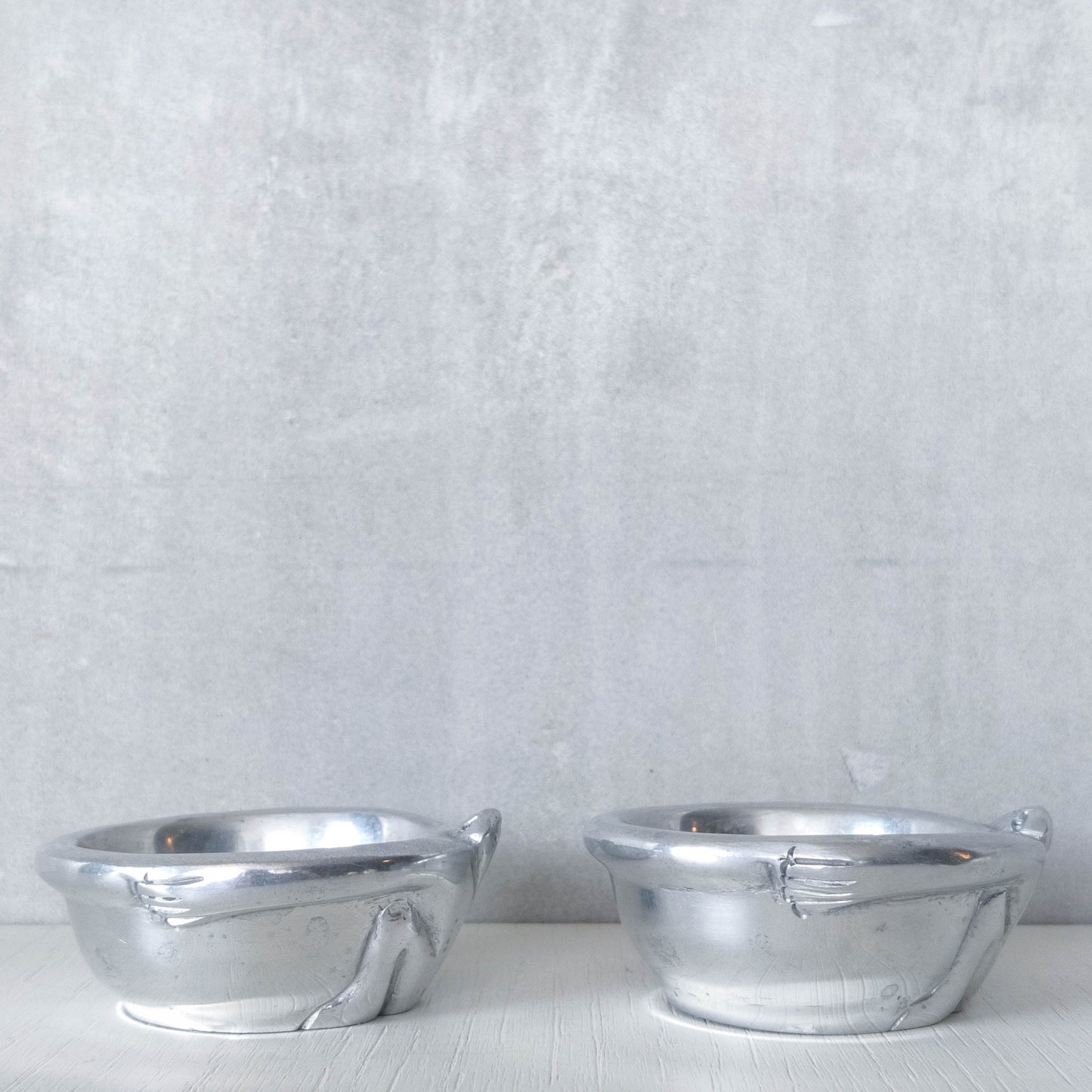 A pair of Carrol Boyes small figural cast aluminium bowls or tea light holders