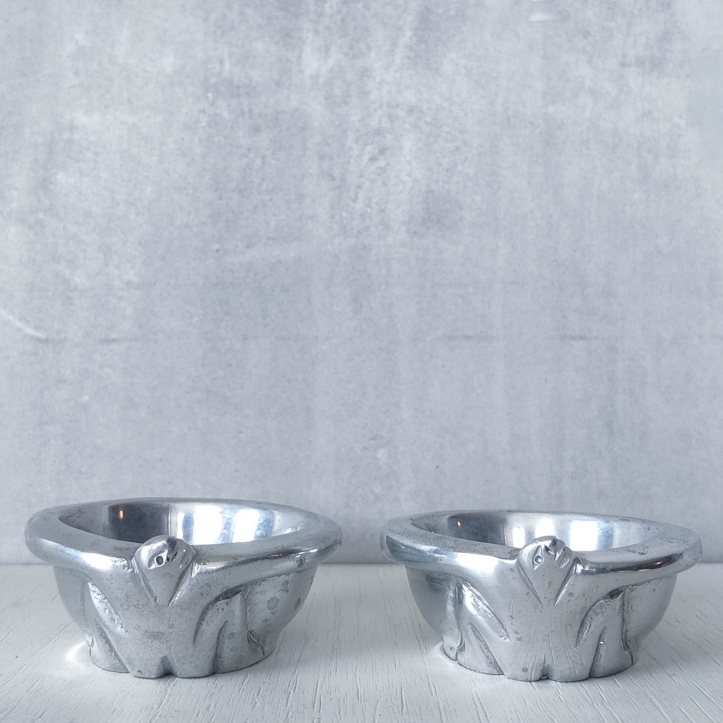 A pair of Carrol Boyes small figural cast aluminium bowls or tea light holders