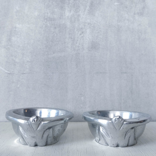 A pair of Carrol Boyes small figural cast aluminium bowls or tea light holders