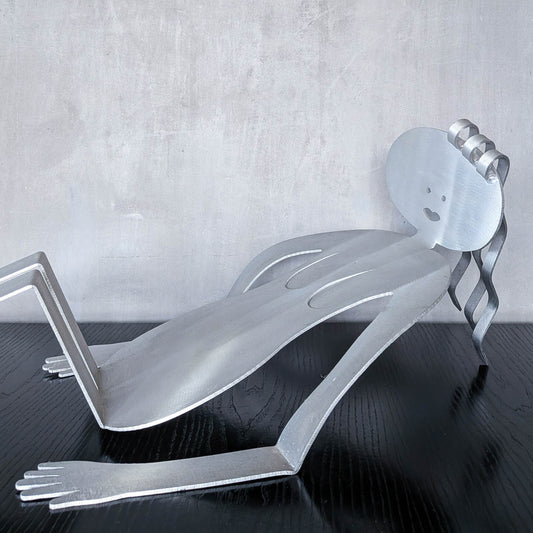 A large vintage 1990s postmodern Fred Garbotz figural brushed aluminium book or record rack