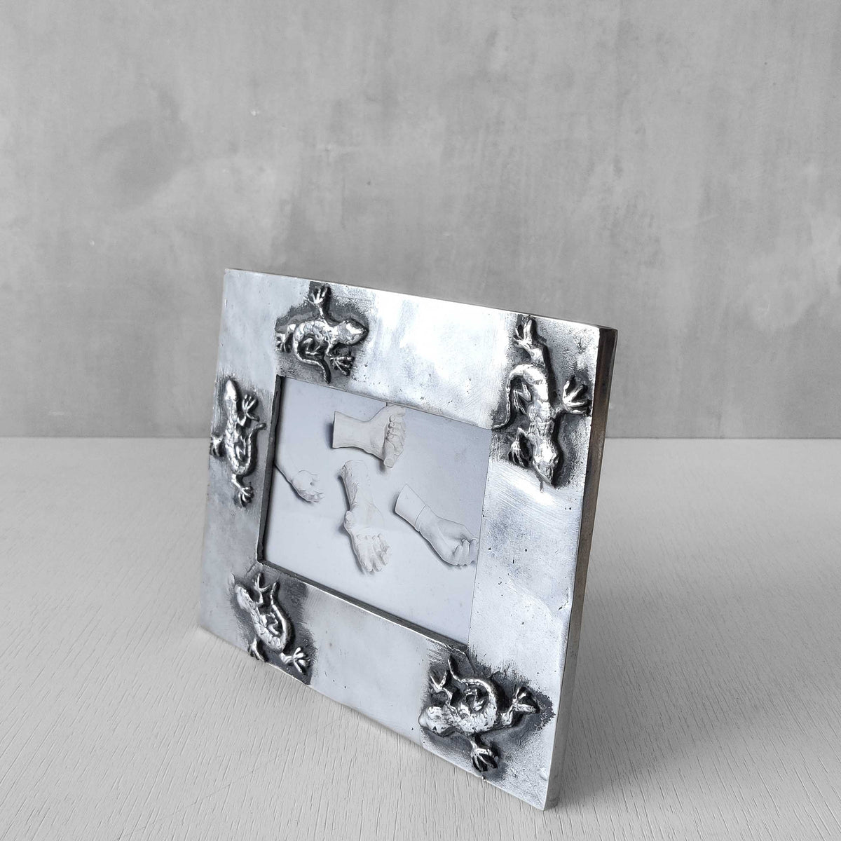 A vintage hand sand cast aluminium photo frame with gecko motifs