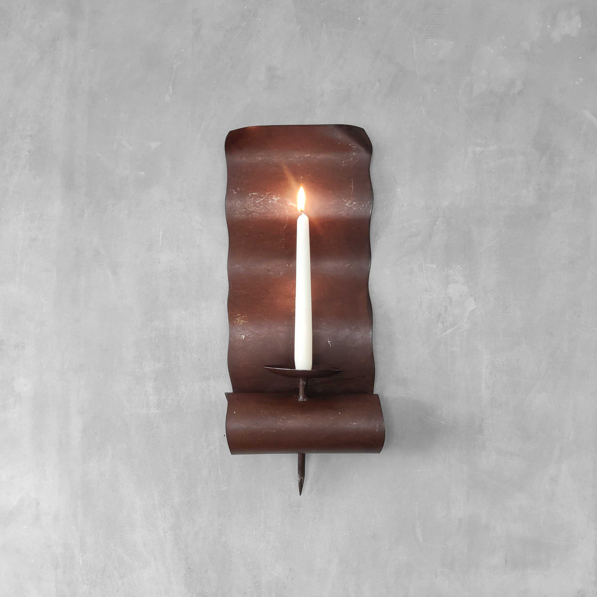 A large steel patinated wavy scrolled sculptural candle sconce