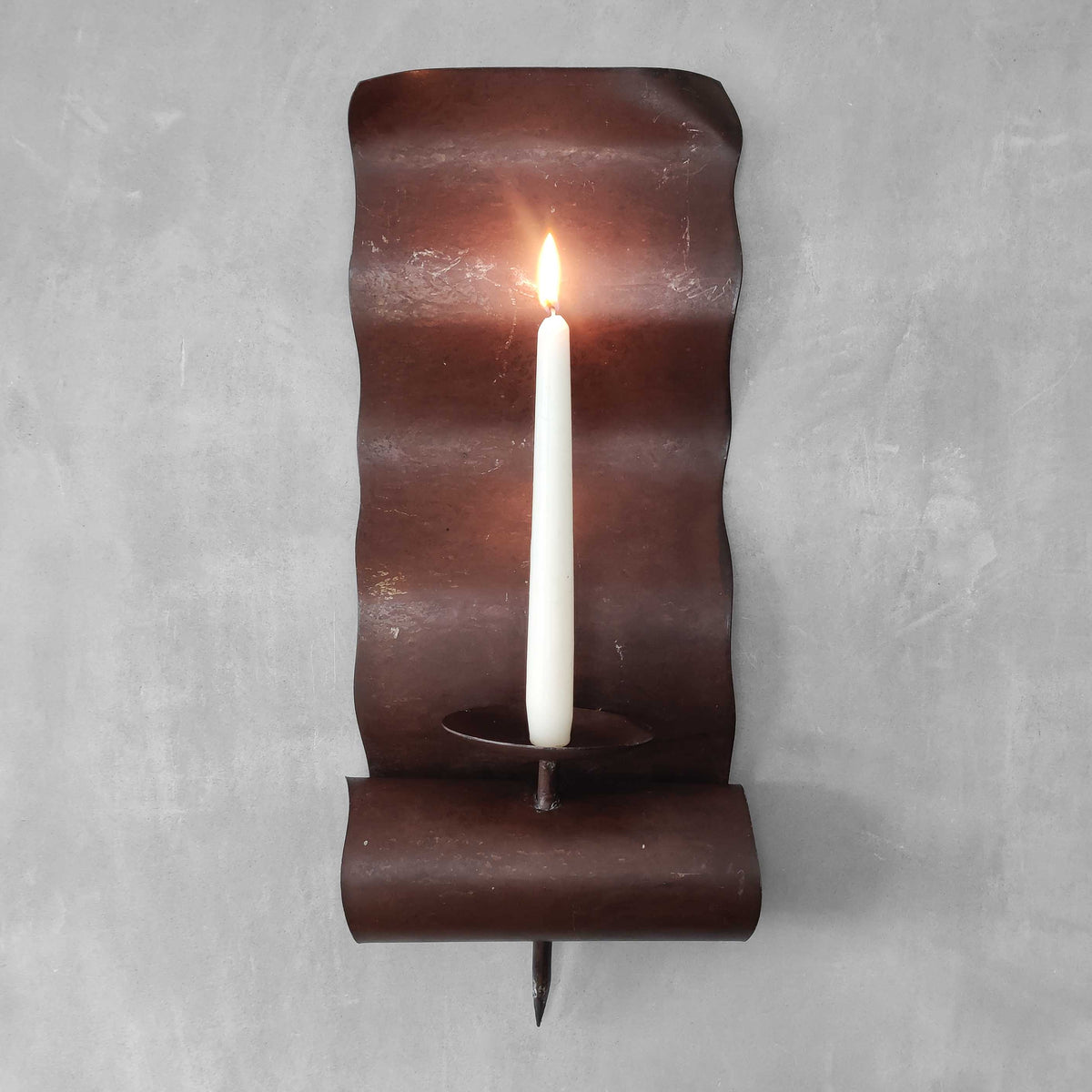 A large steel patinated wavy scrolled sculptural candle sconce