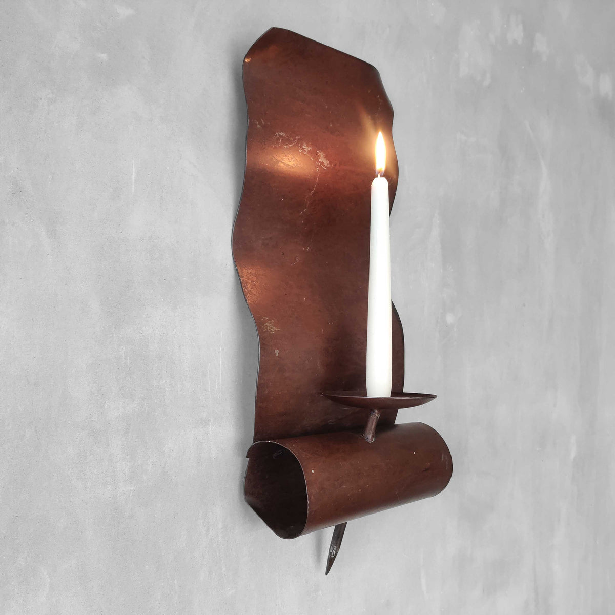 A large steel patinated wavy scrolled sculptural candle sconce