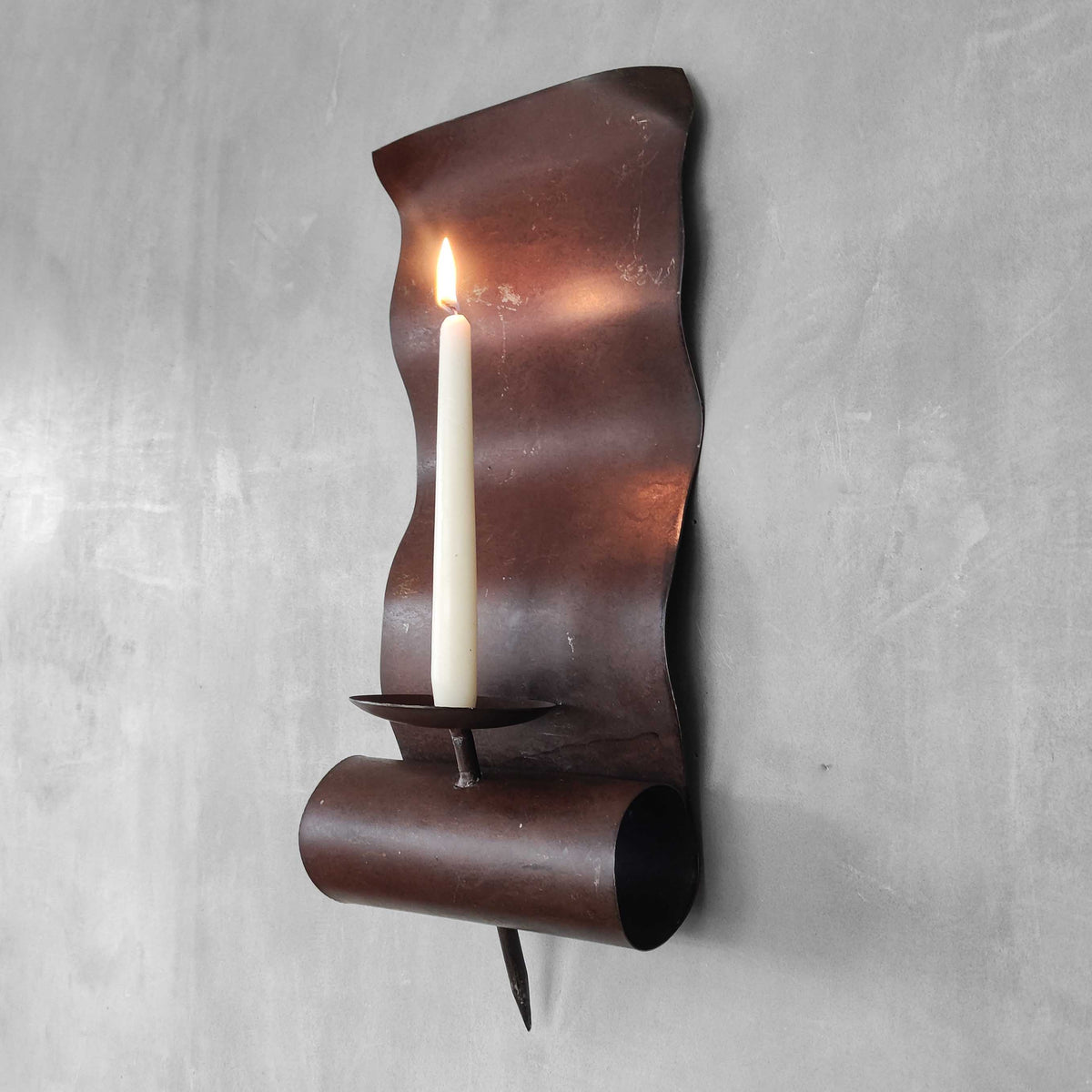 A large steel patinated wavy scrolled sculptural candle sconce