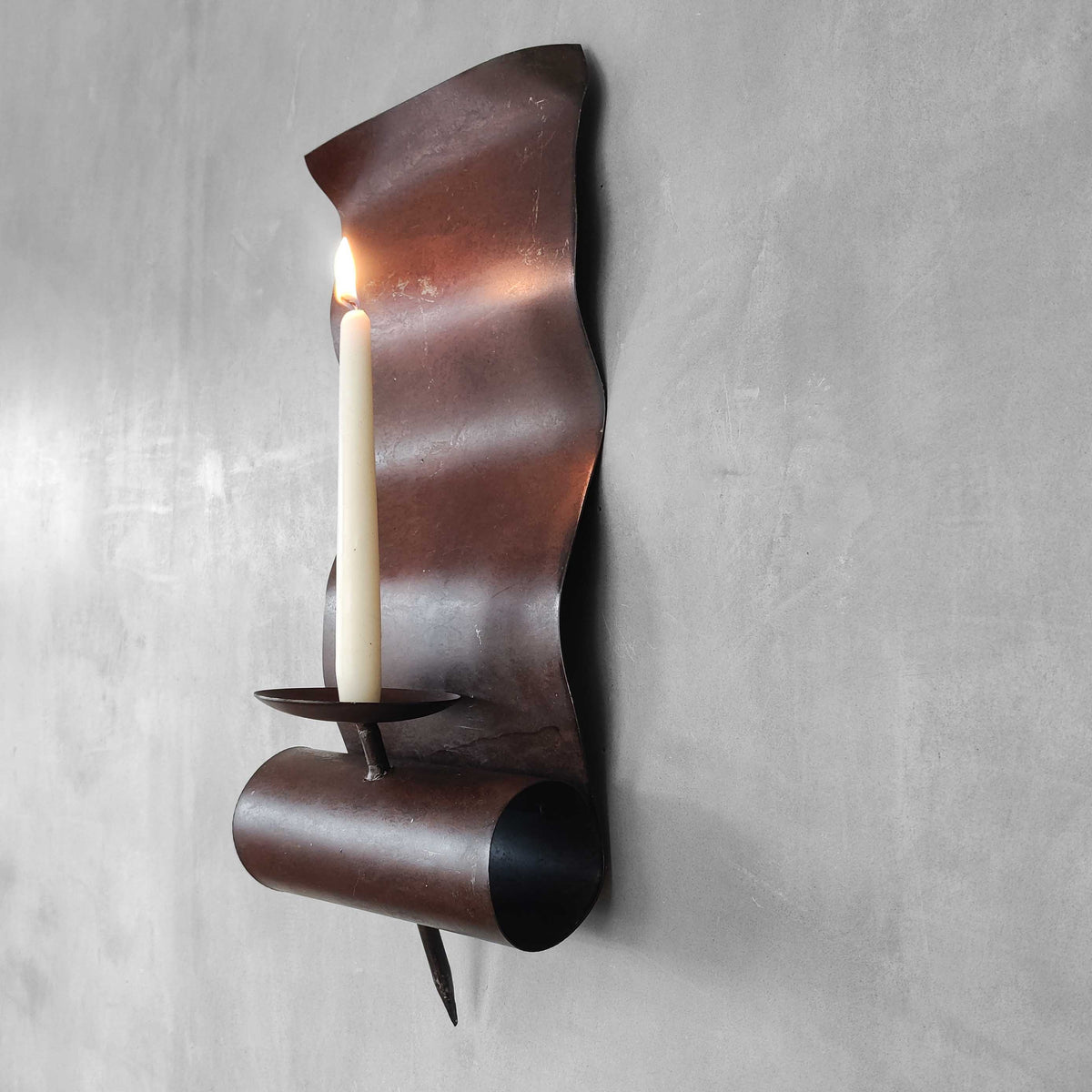 A large steel patinated wavy scrolled sculptural candle sconce