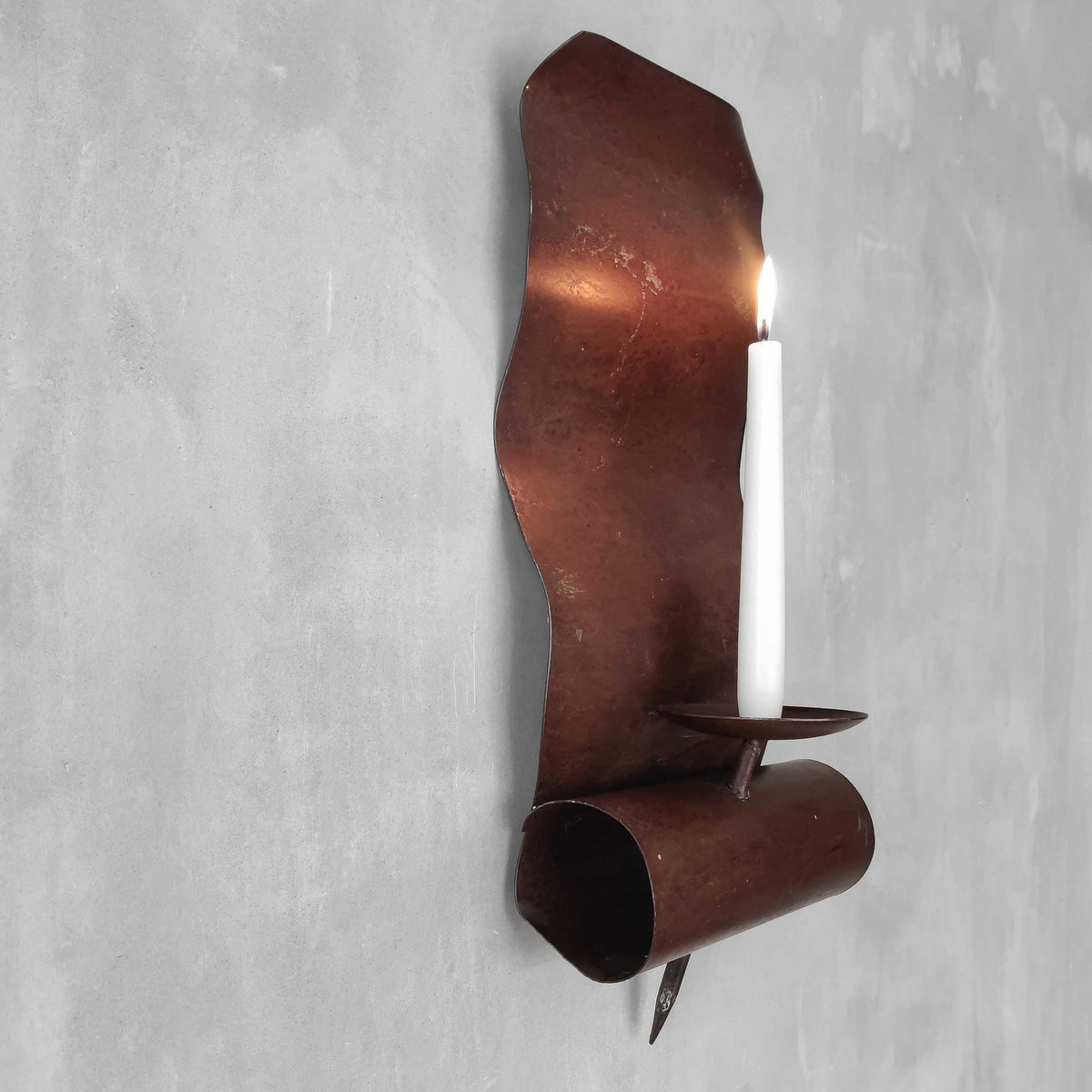 A large steel patinated wavy scrolled sculptural candle sconce
