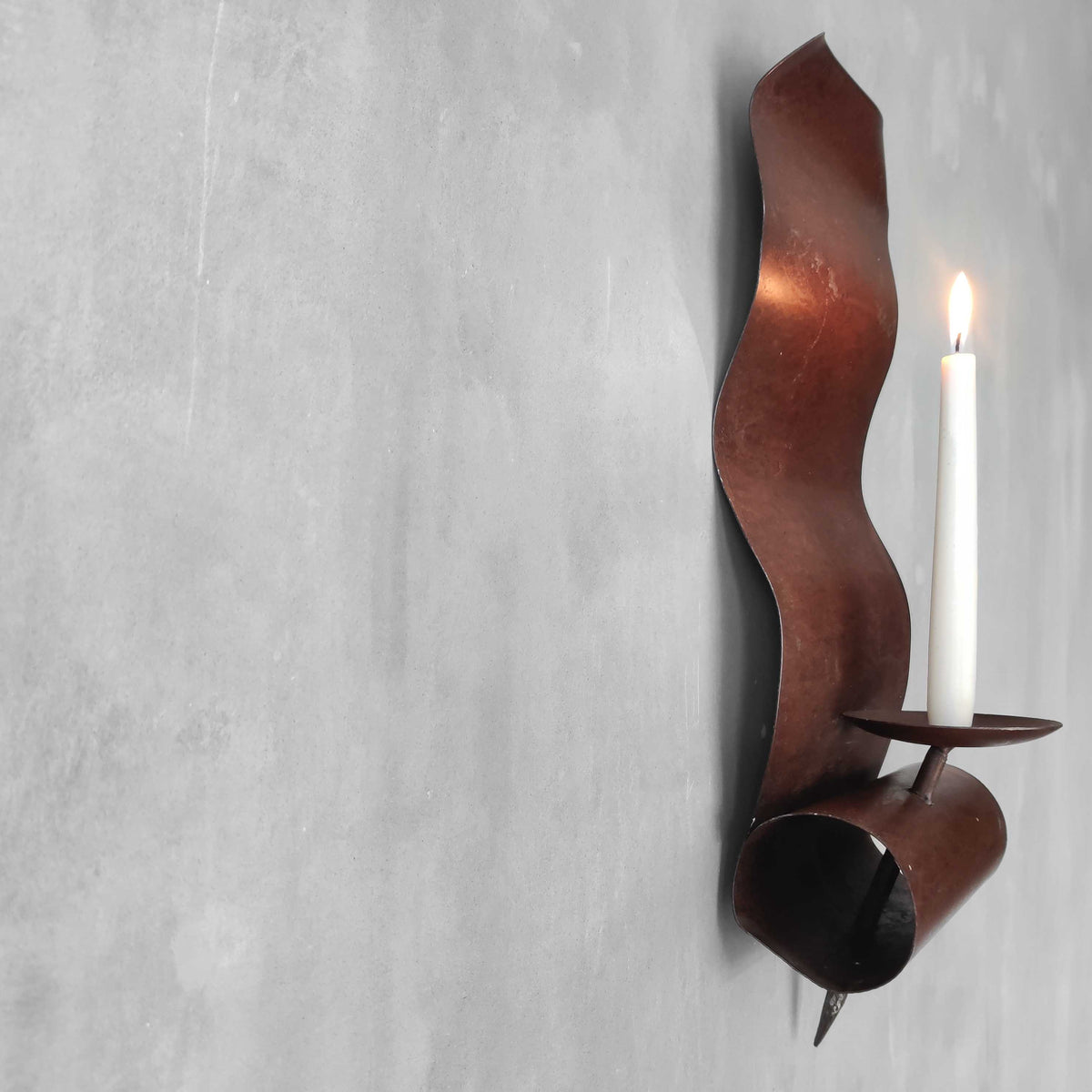 A large steel patinated wavy scrolled sculptural candle sconce