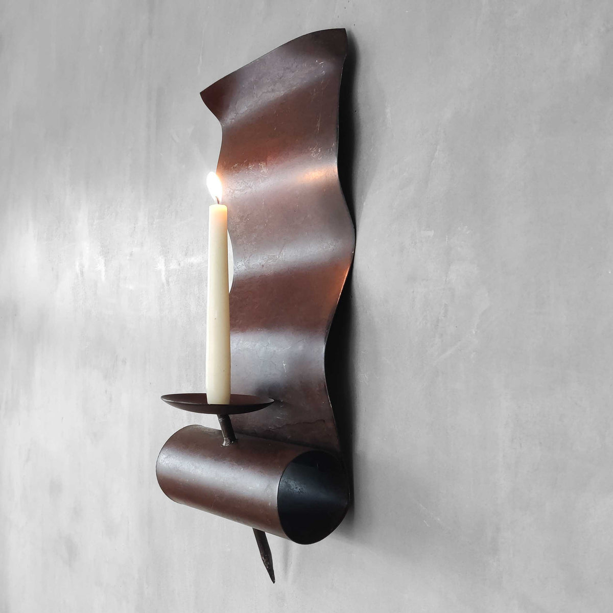 A large steel patinated wavy scrolled sculptural candle sconce