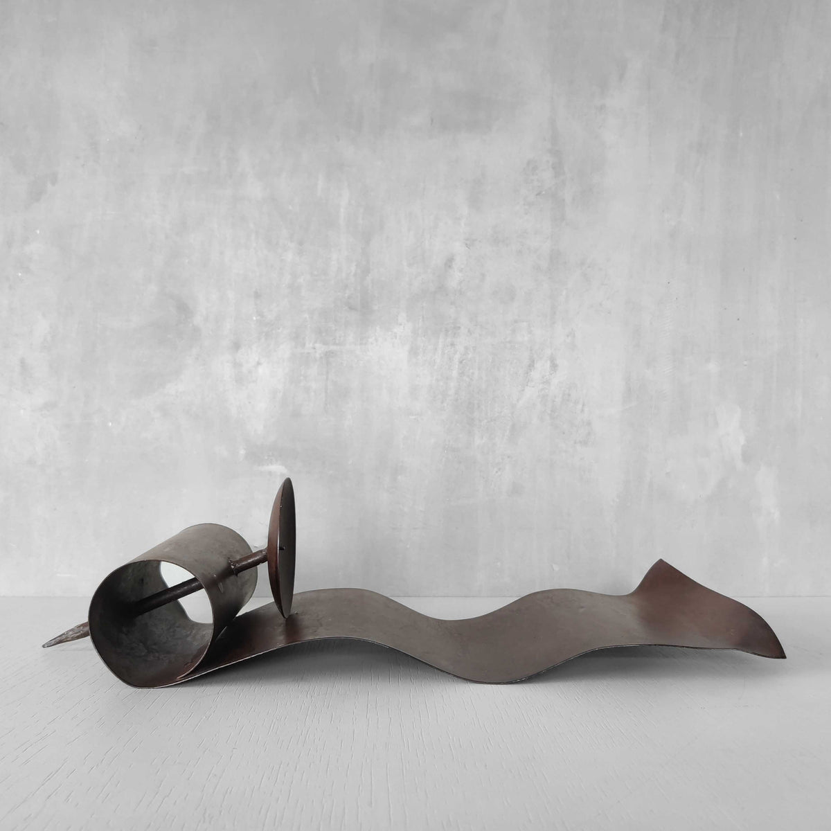 A large steel patinated wavy scrolled sculptural candle sconce