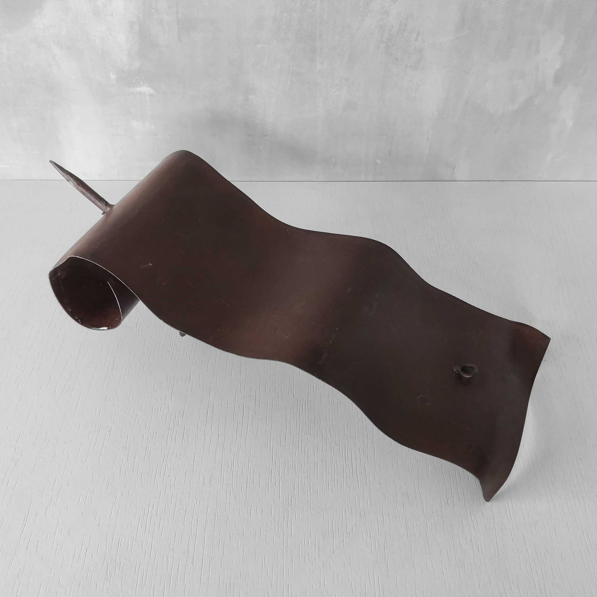 A large steel patinated wavy scrolled sculptural candle sconce