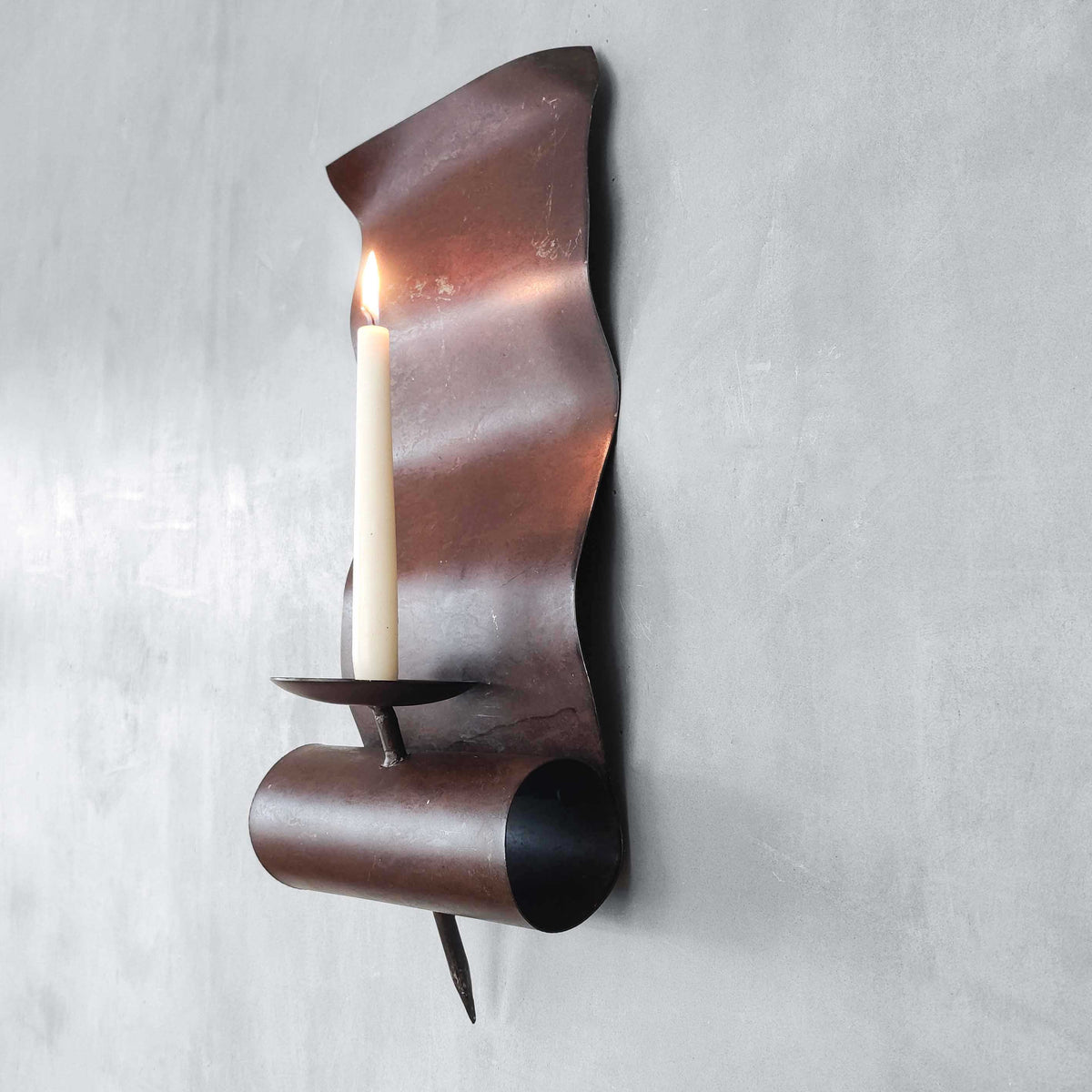 A large steel patinated wavy scrolled sculptural candle sconce